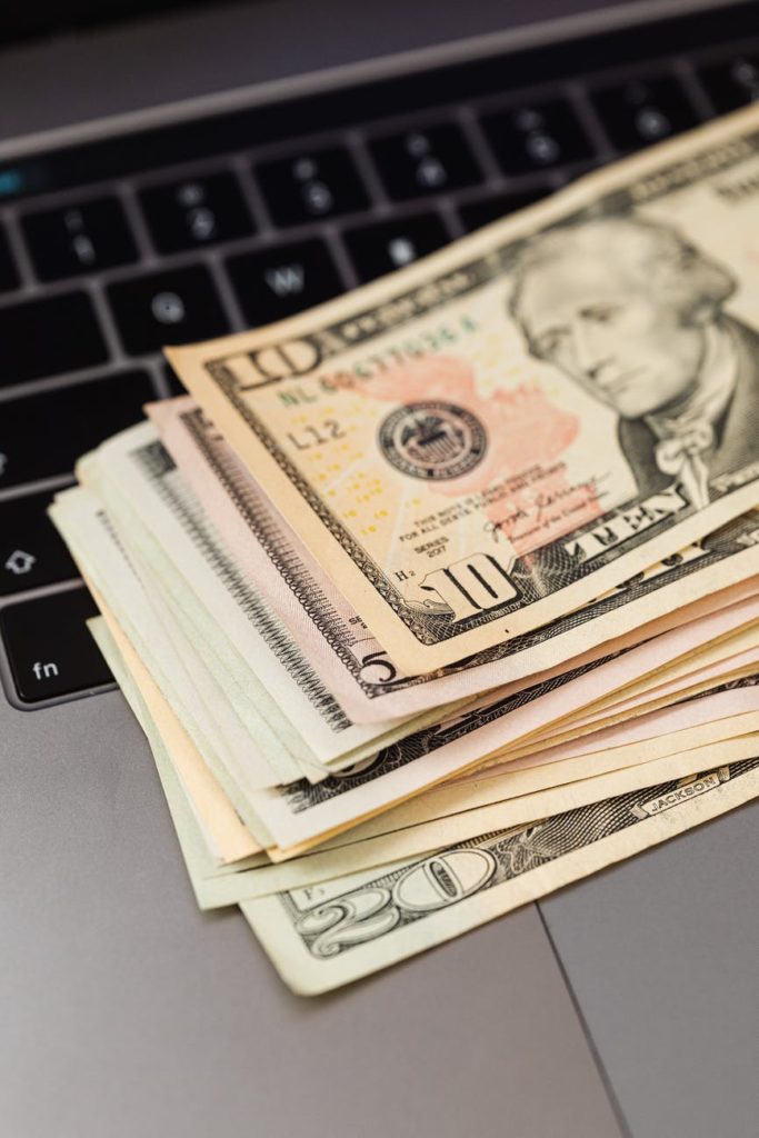 dollar bills on top of a laptop
