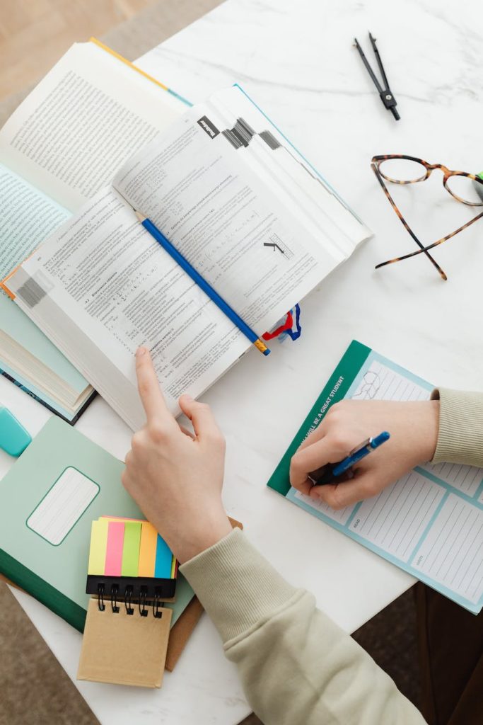 close up of person sitting at desk studying with textbooks